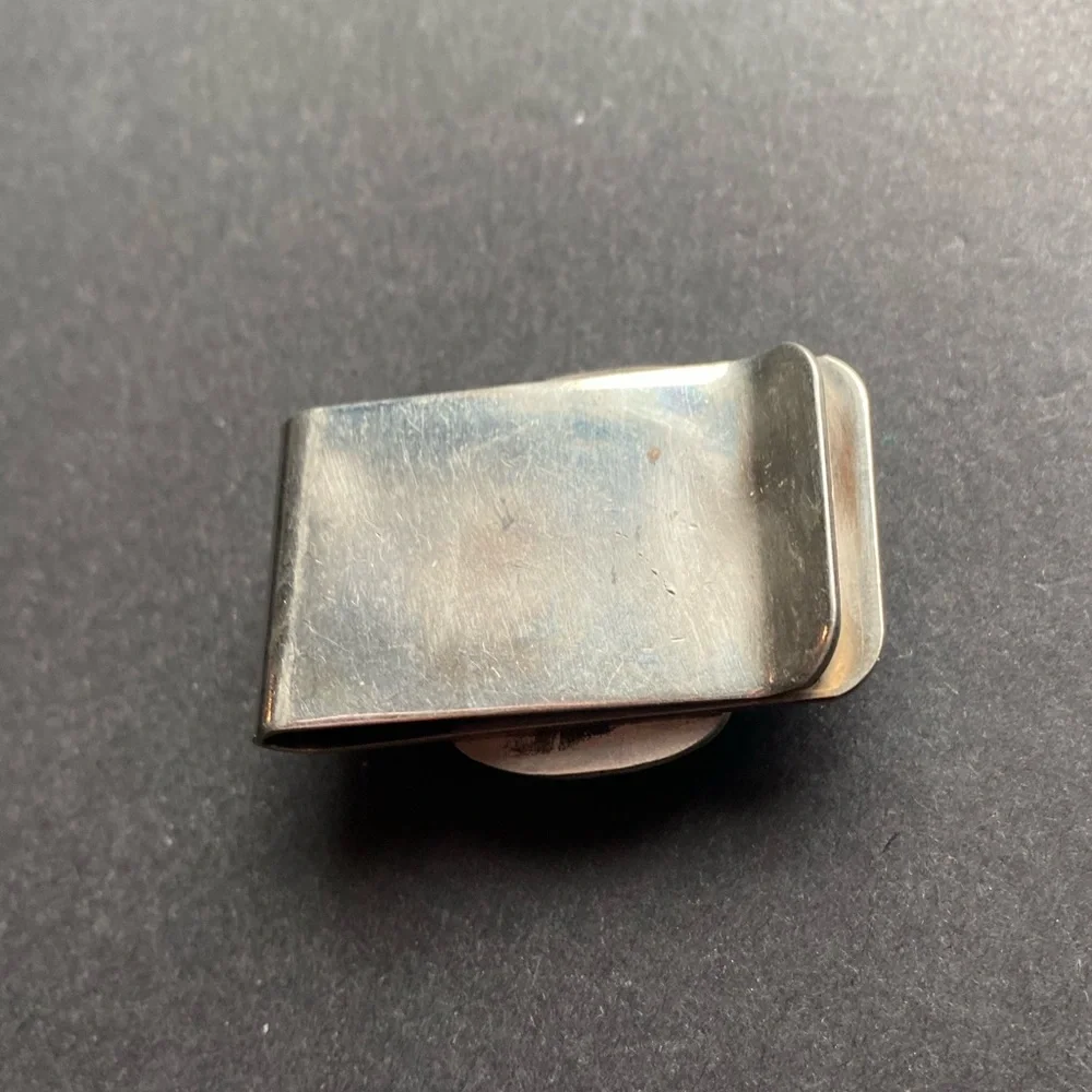 Silver toned money clip with polished blue stone. No stamps.